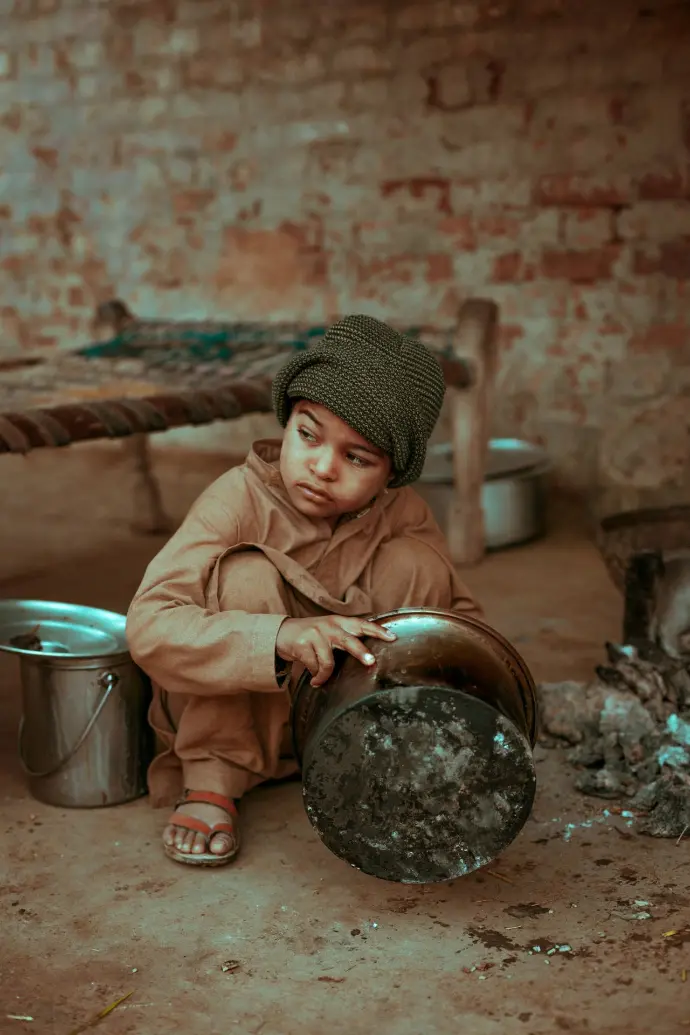 poor boy holding stock pot