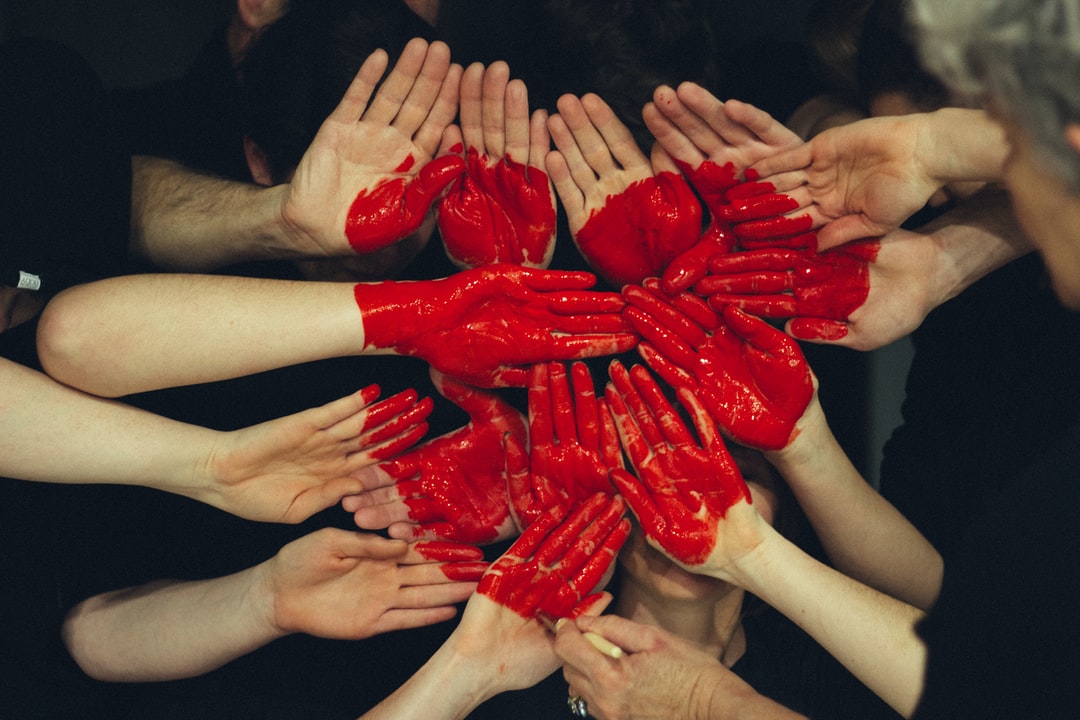a bunch of hands together with a red painted heart on them
